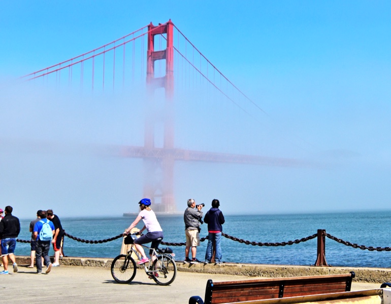 People biking and walking in front of the Golden Gate Bridge