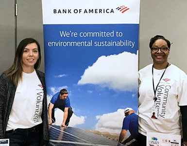 Two women smiling next to a Bank of america - We are committed to environmental sustainability banner